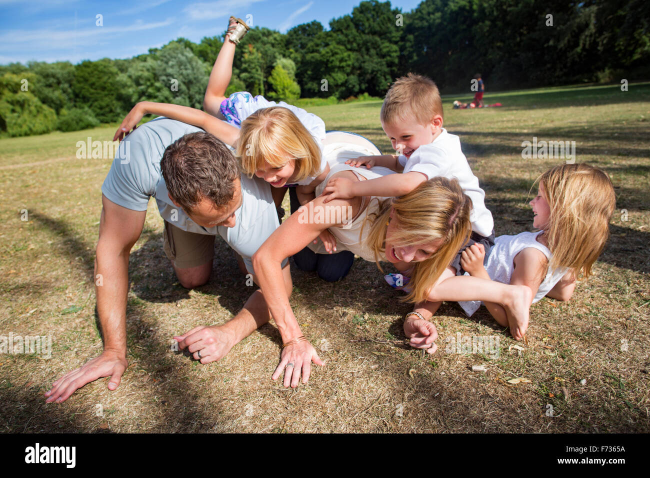 Famiglia con tre bambini che giocano in un parco. Foto Stock