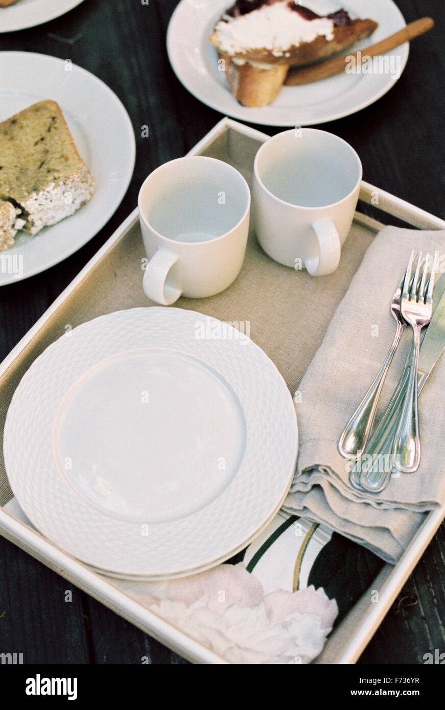 Angolo di alta vista di un vassoio con tazze, piatti e posate, pasticceria. Foto Stock