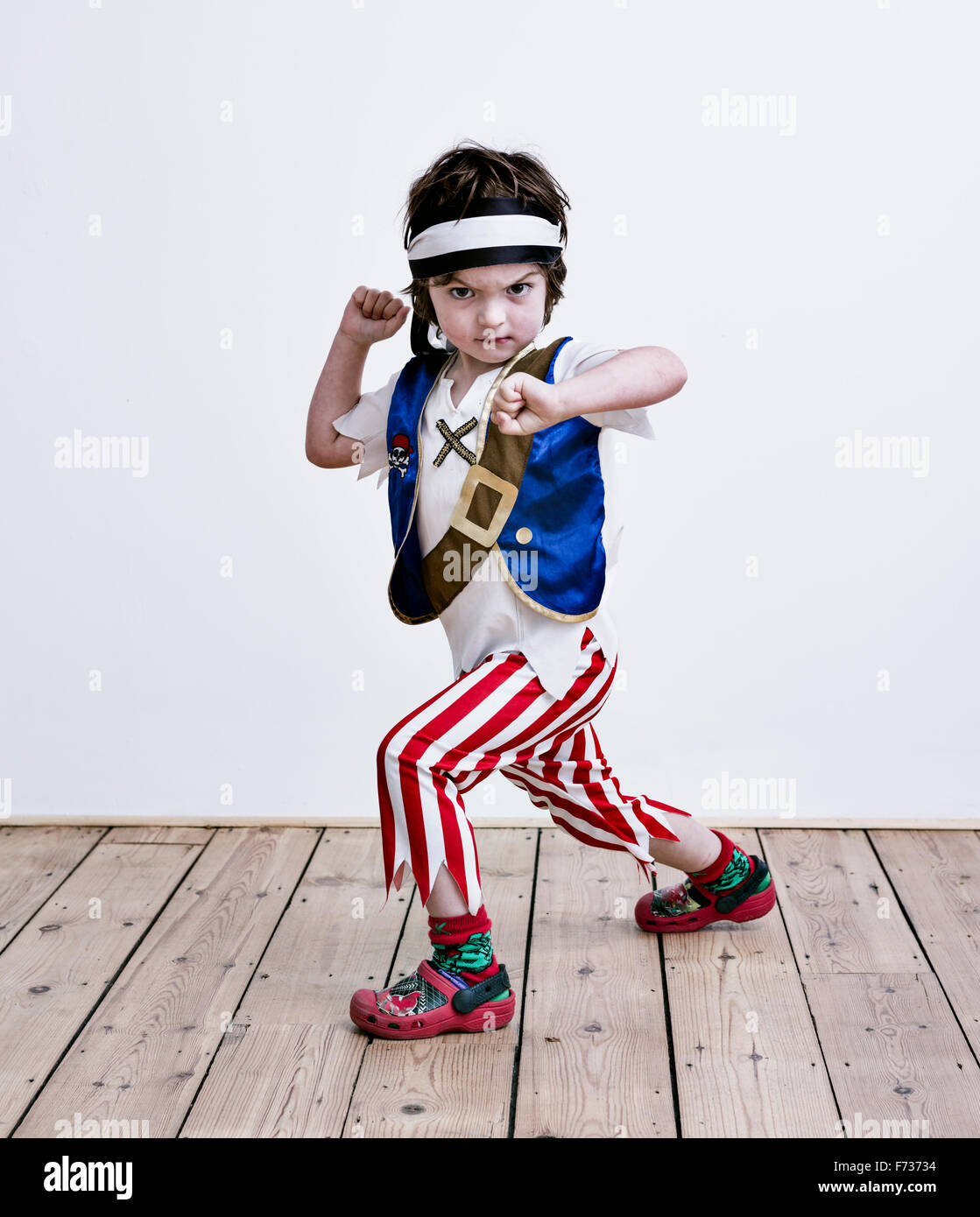 Un ragazzo in fancy dress costume, pantalone a righe e una cinghia, vestito come un pirata. Foto Stock