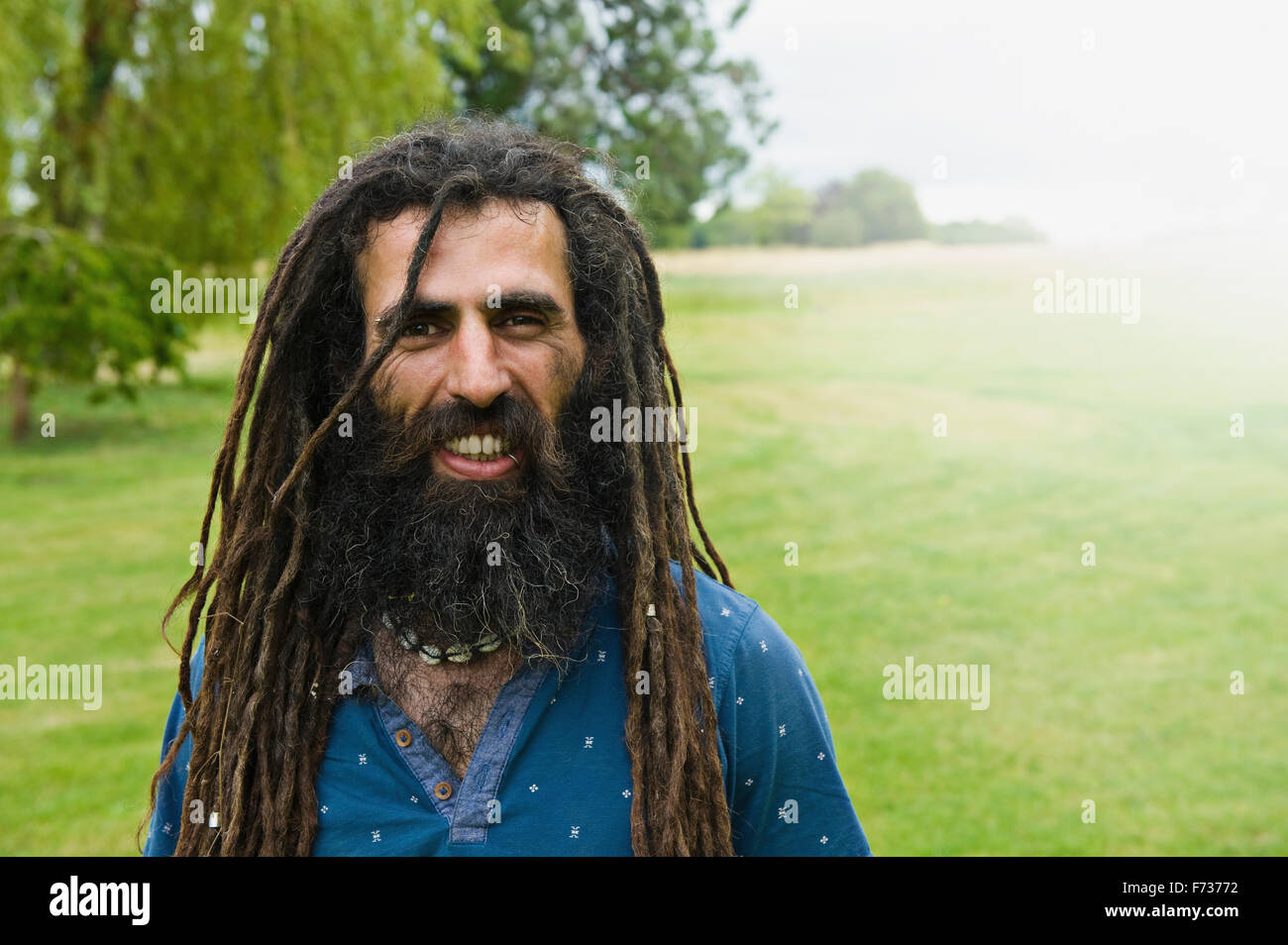 Un uomo con lunghi dreadlocks in una maglietta blu. Foto Stock