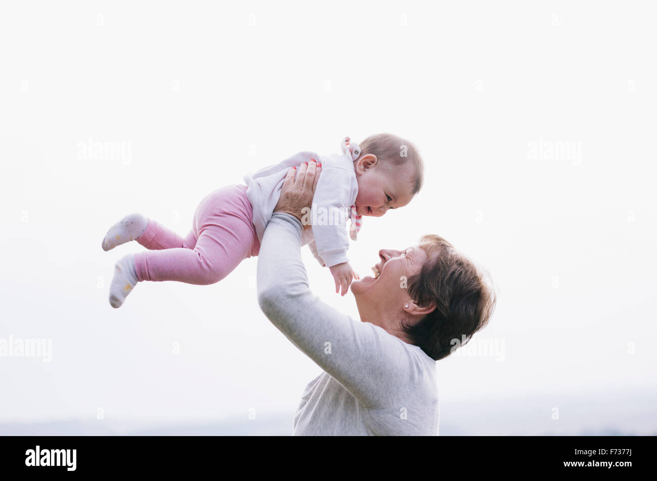 Una donna che tiene una bambina in aria sopra la sua testa. Foto Stock