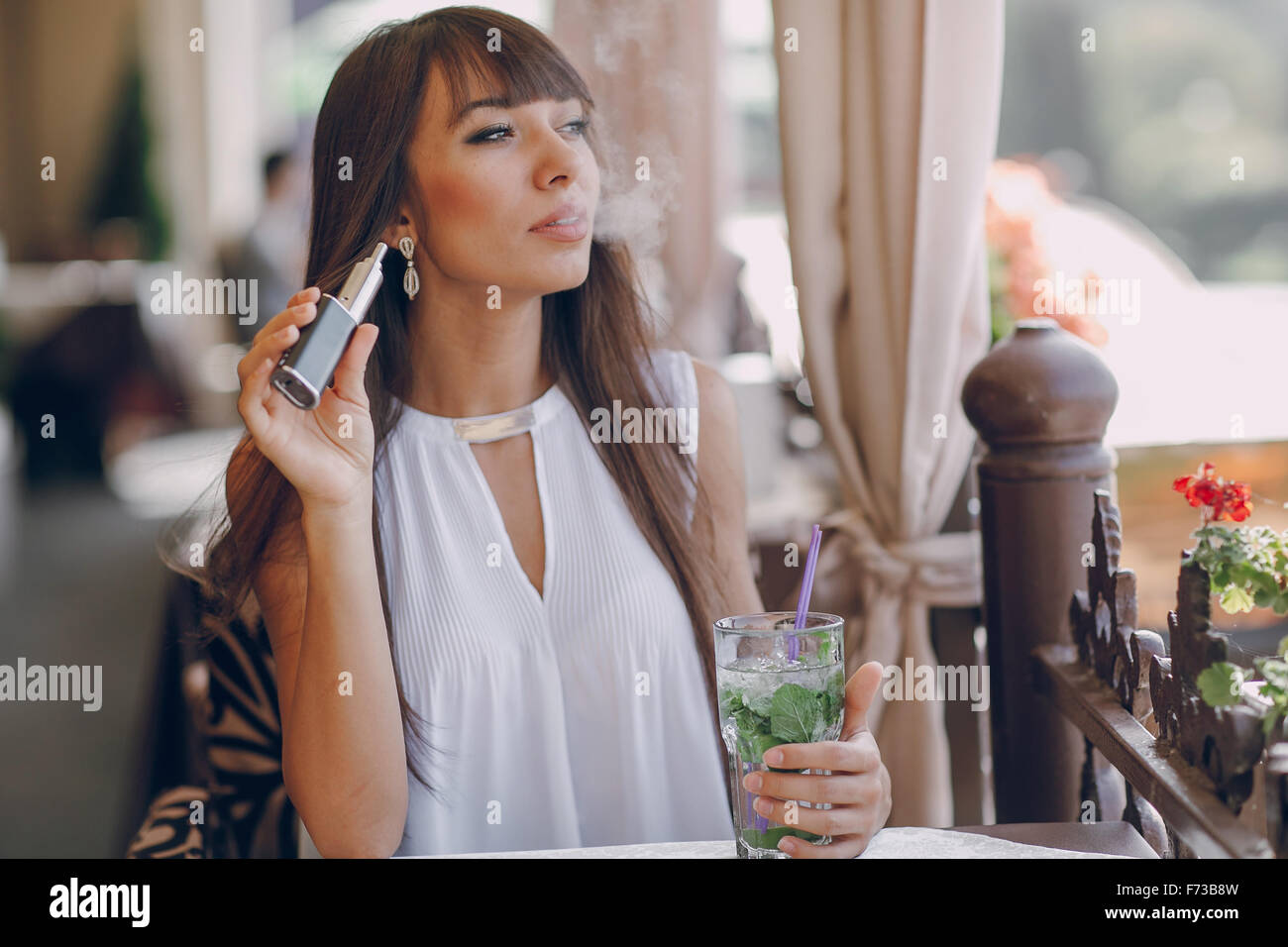 Girn in cafe con E-sigaretta Foto Stock