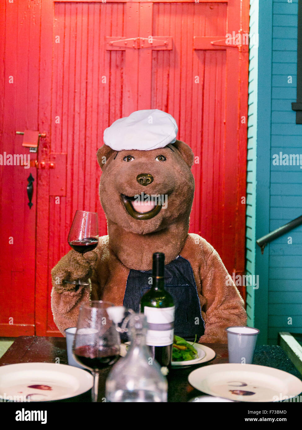 Una persona in costume di orso detiene un drink sulla sua mano destra in un drink party. Foto Stock