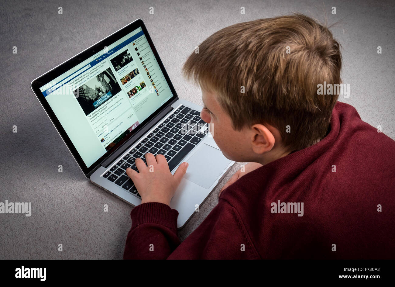 Un ragazzo guardando Facebook su un computer portatile Foto Stock
