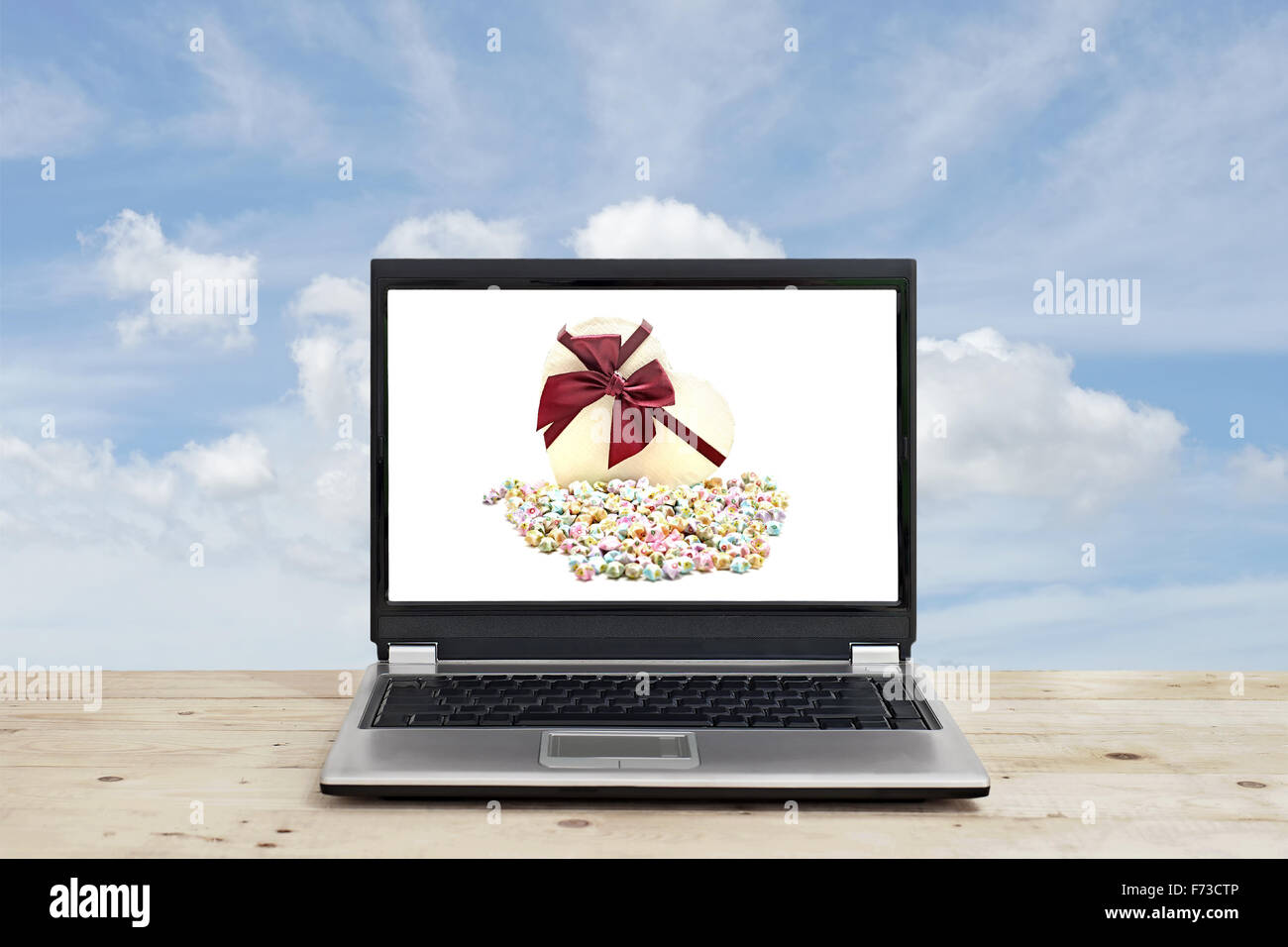 Confezione regalo e origami lucky stelle su schermo di computer portatile con sfondo cielo Foto Stock