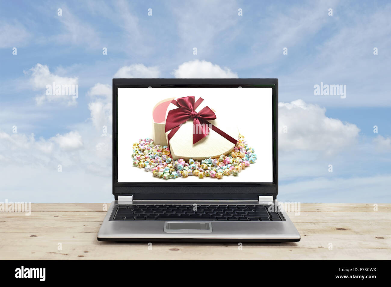 Confezione regalo e origami lucky stelle su schermo di computer portatile con sfondo cielo Foto Stock