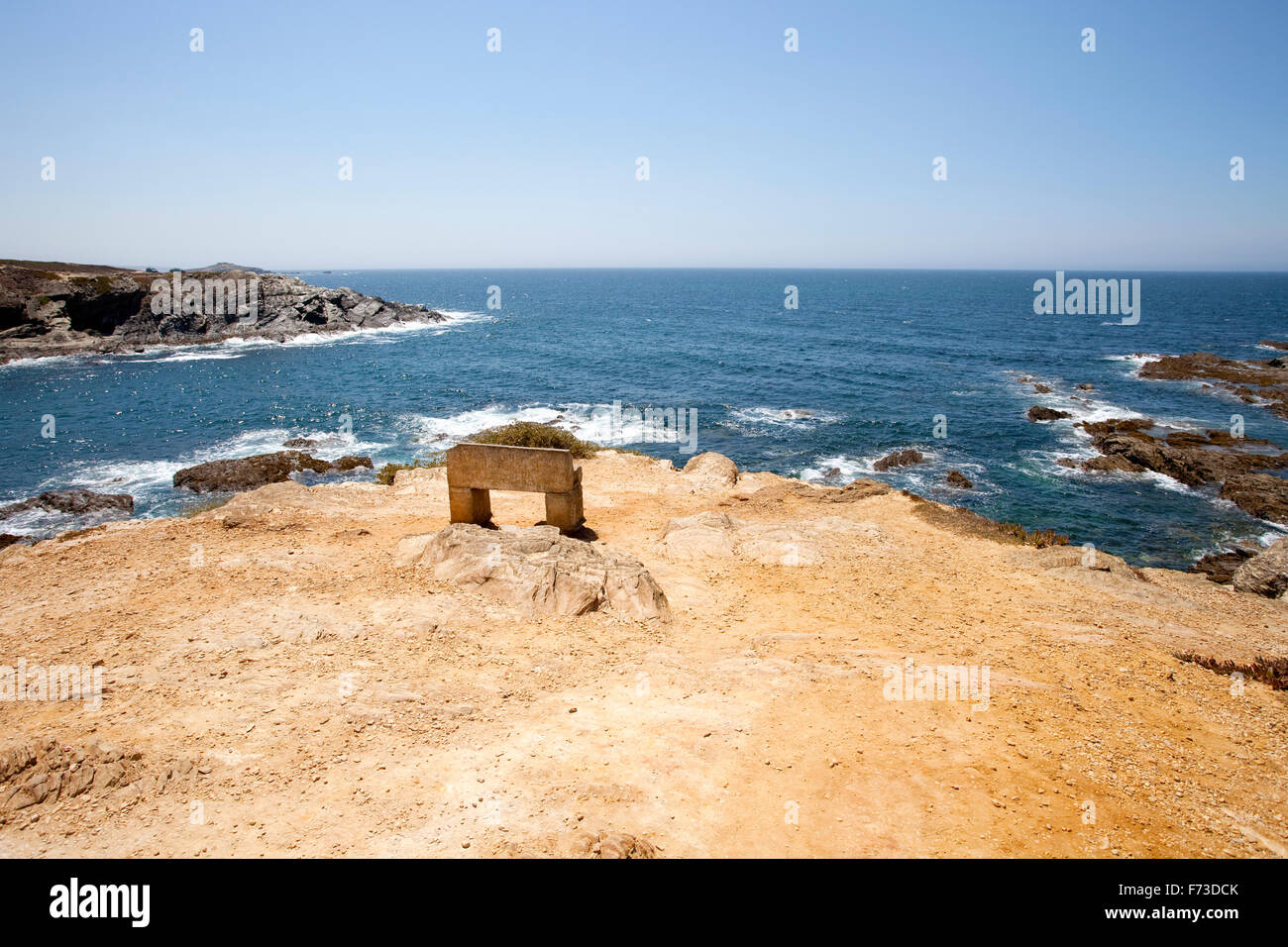 Un banco di pietra di fronte all'Oceano Atlantico, Porto Covo, Alentejo, Portogallo. Foto Stock