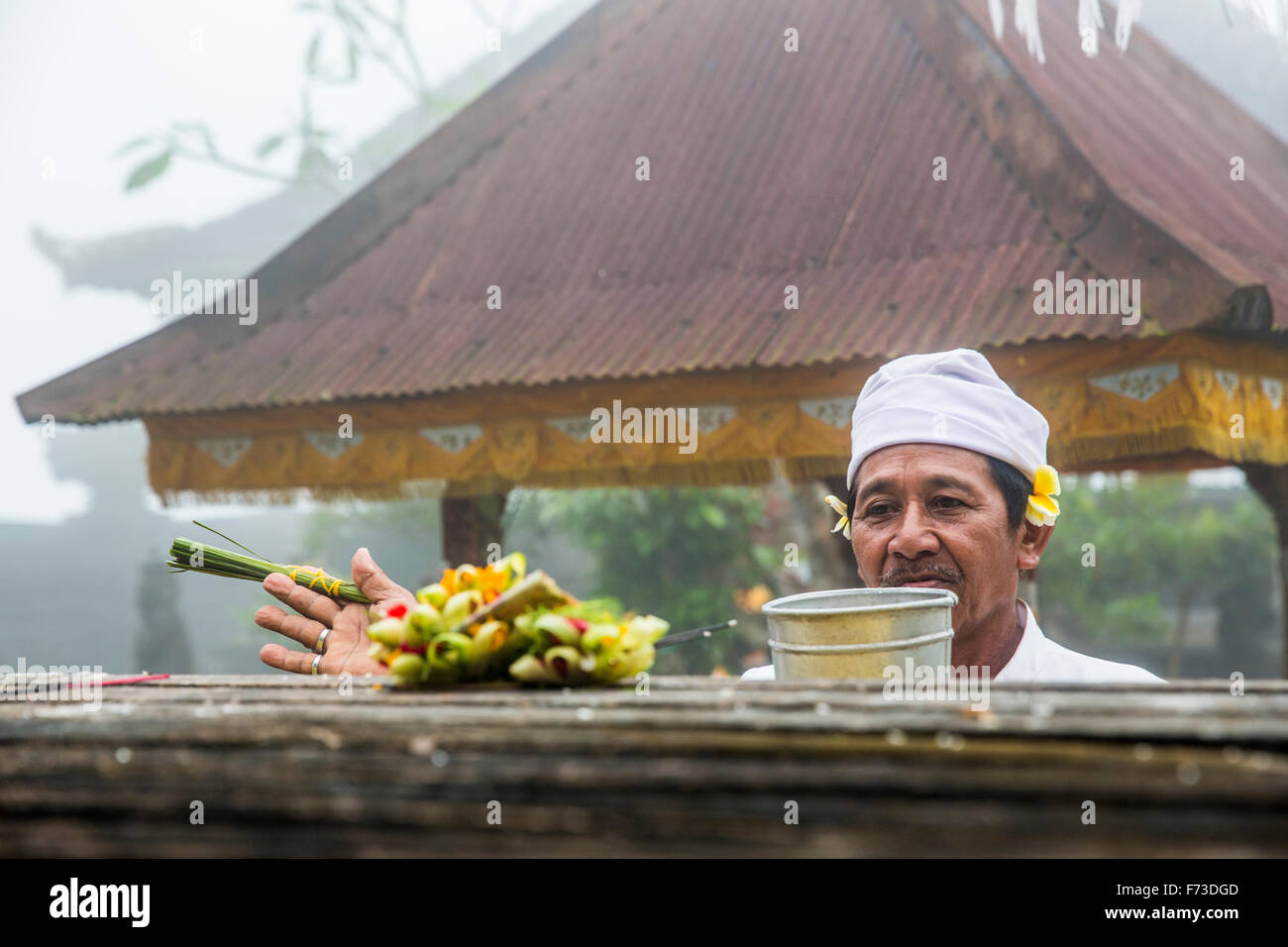 Alta uomo santo esegue una benedizione in un tempio indonesiano a Bali, in Indonesia Foto Stock