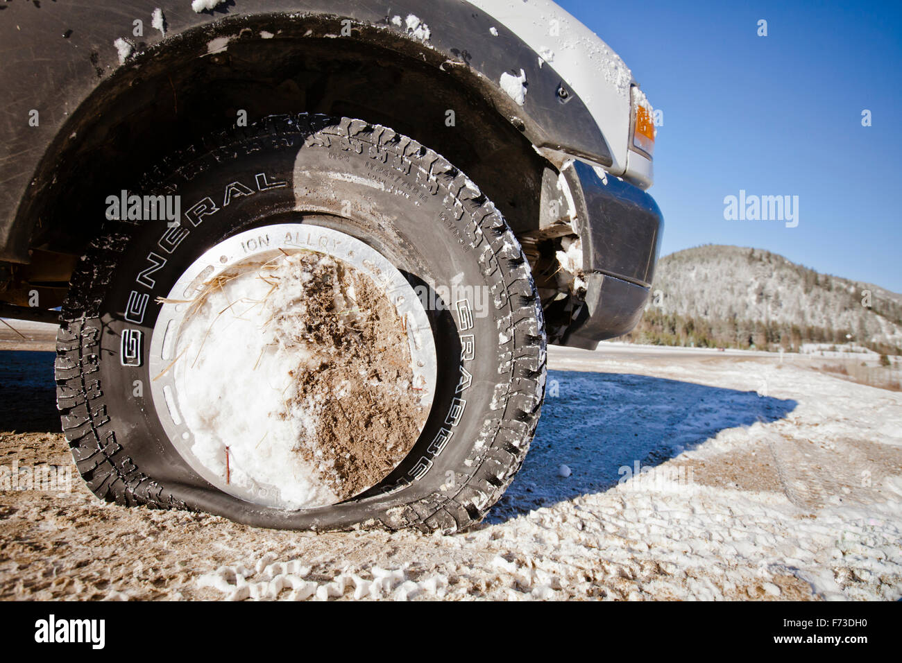 Pneumatico sgonfio e il cappuccio del mozzo riempita con la neve e la sporcizia. Foto Stock