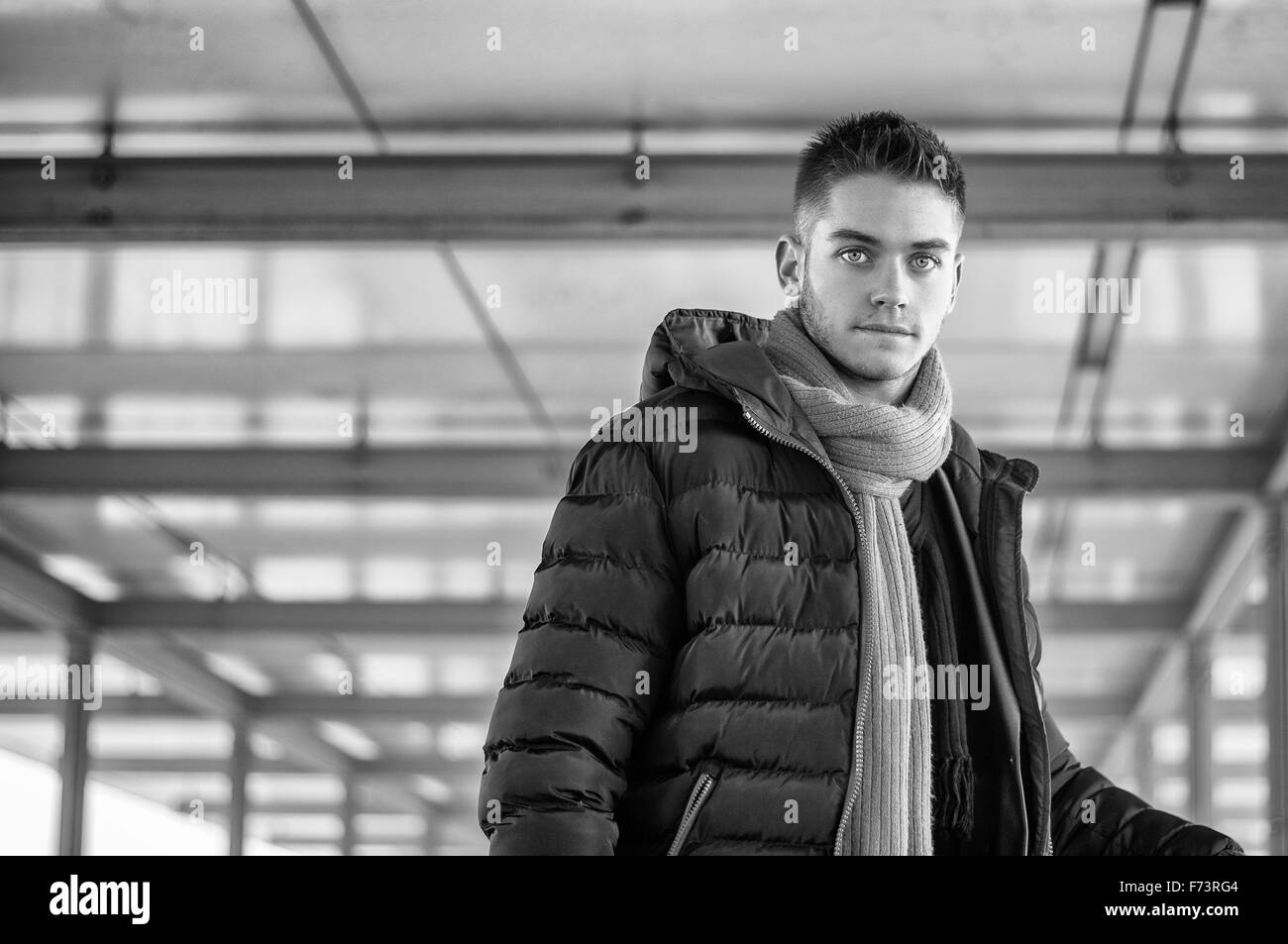 Belli i giovani alla moda uomo in piedi su un marciapiede che indossa una camicia alla moda e sciarpa in un rilassato fiducioso pongono guardando c Foto Stock