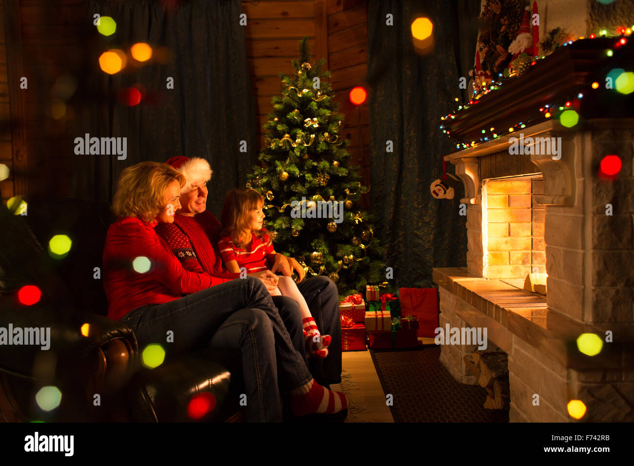 La famiglia felice da un camino a Christmastime Foto Stock