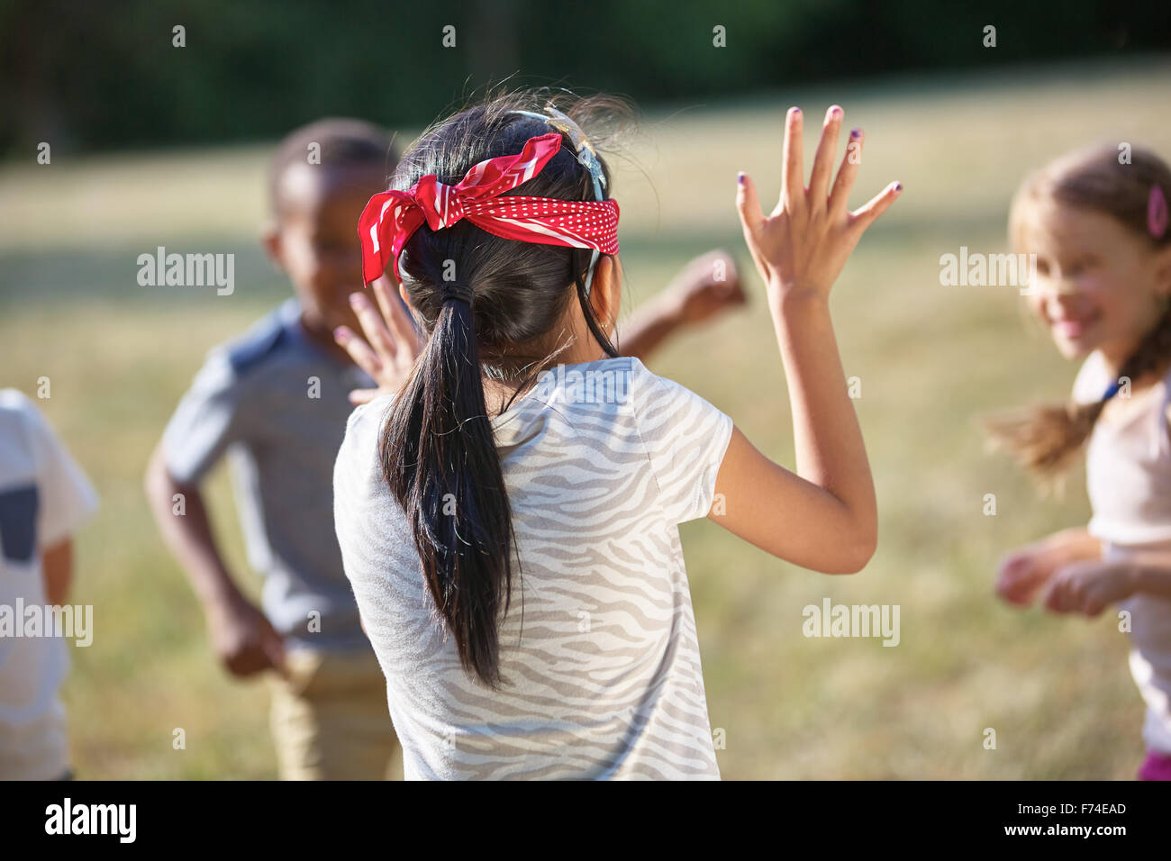 I bambini divertendosi cieco il buff al parco Foto Stock