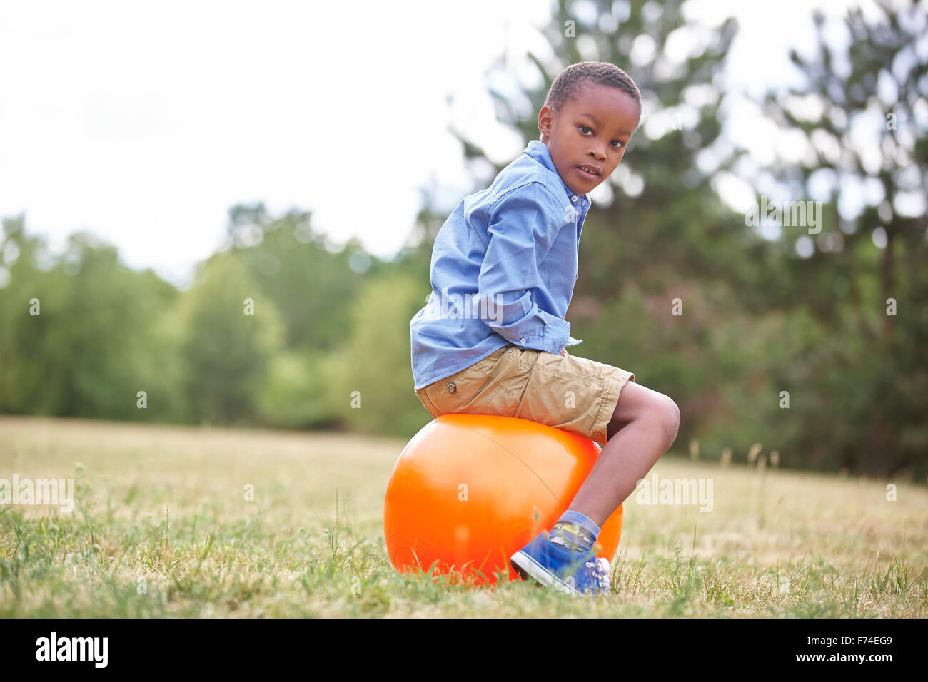 Ragazzo africano seduto su un spacehooper presso il parco Foto Stock