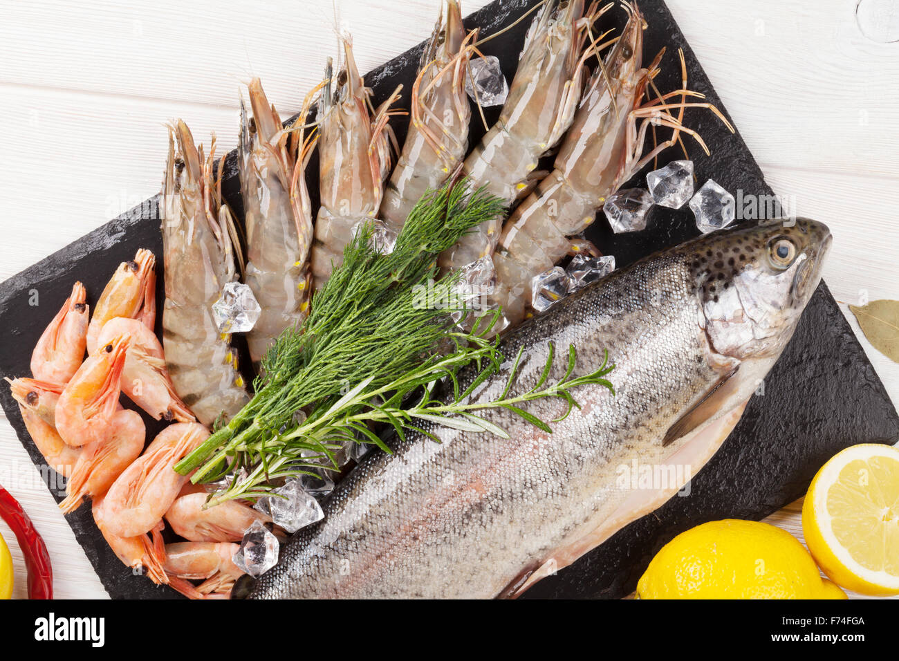 Crudo fresco il cibo del mare con spezie sulla lastra di pietra su un tavolo di legno dello sfondo. Vista superiore Foto Stock