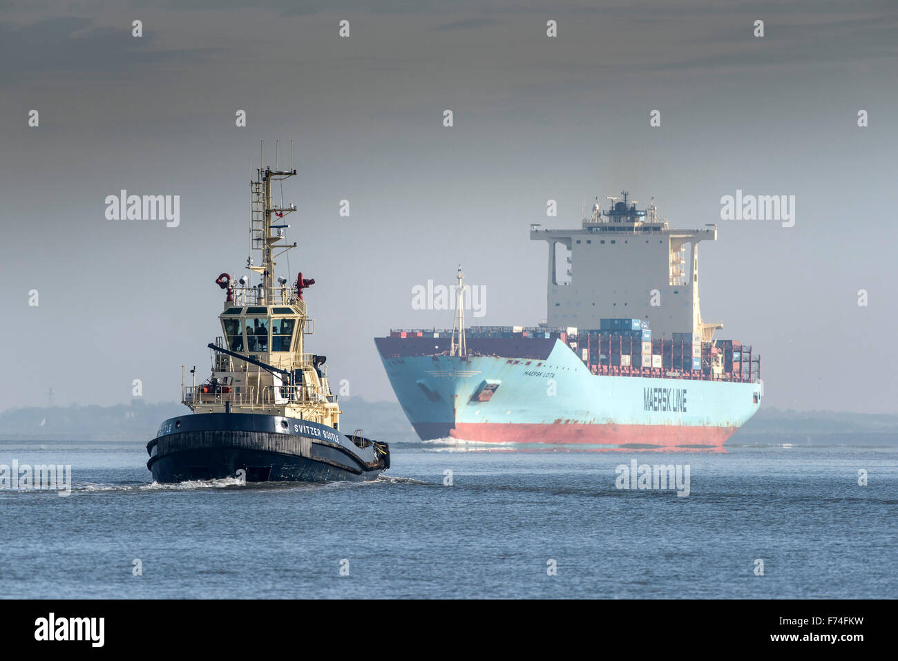 Il rimorchiatore Svitzer Bootle accompagna il contenitore nave Maersk Lota come lei cuoce a vapore più a monte lungo il fiume Tamigi. Foto Stock