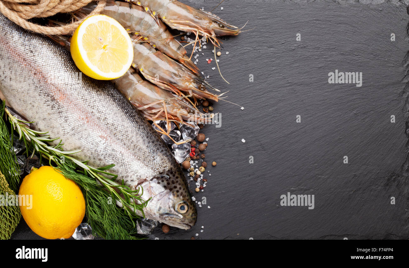 Crudo fresco il cibo del mare con spezie sulla pietra nera dello sfondo. Vista da sopra con lo spazio di copia Foto Stock