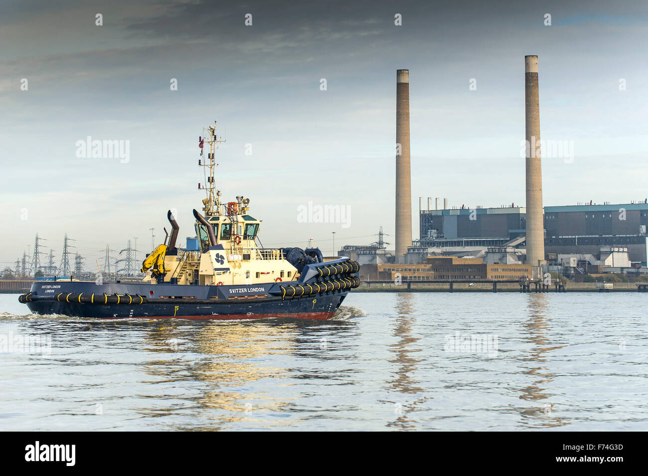 Il rimorchiatore, Svitzer Londra, passa Tilbury B power station in Essex come si cuoce a vapore downriver sul Fiume Tamigi. Foto Stock