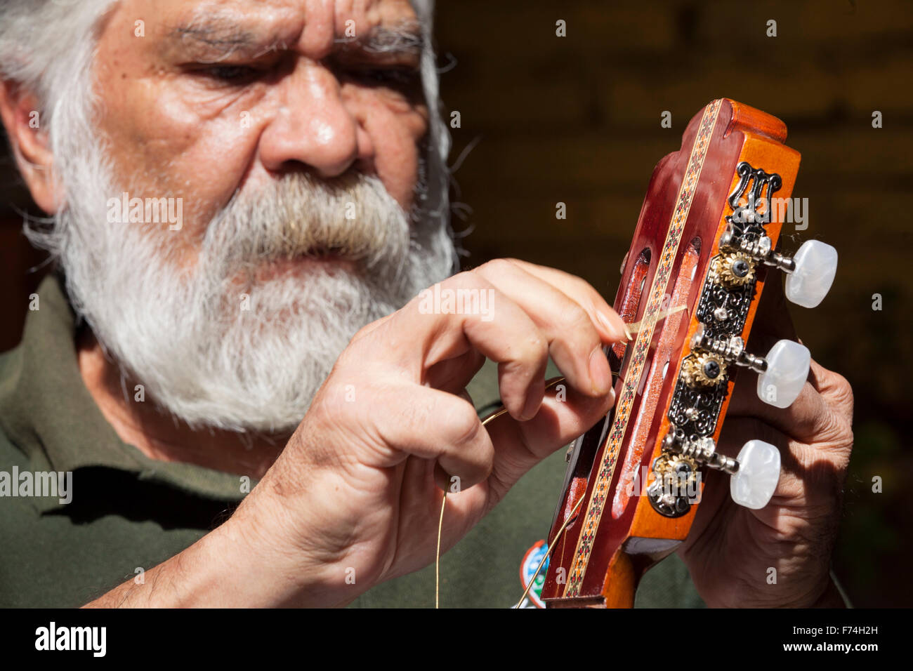 Liutaio Sistos Pasaye stringhe di uno dei suoi prodotti al di fuori di un negozio a Paracho, Michoacan, Messico. Foto Stock