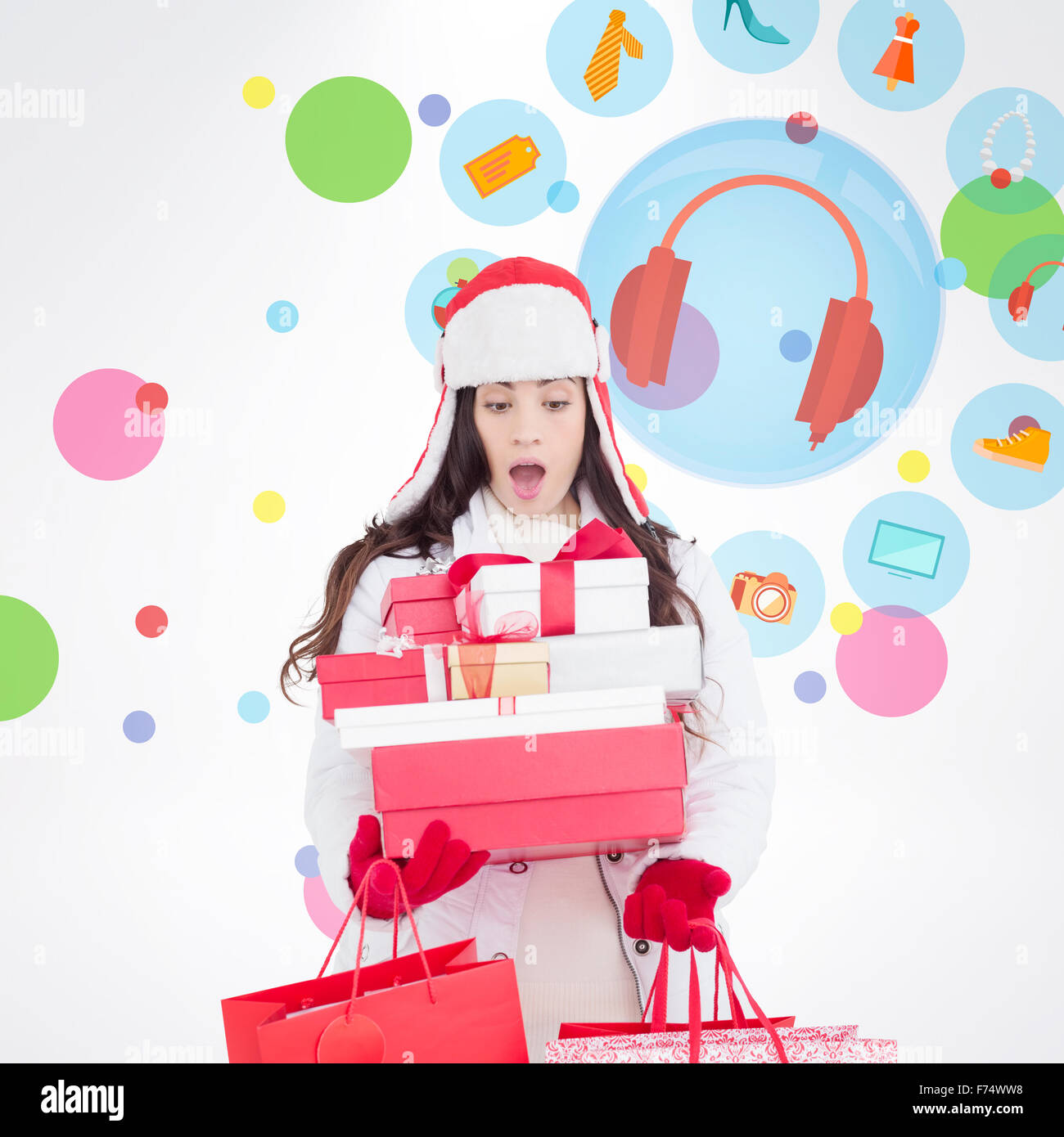 Immagine composita di sorpreso brunette in abbigliamento invernale azienda molti doni e borse per lo shopping Foto Stock