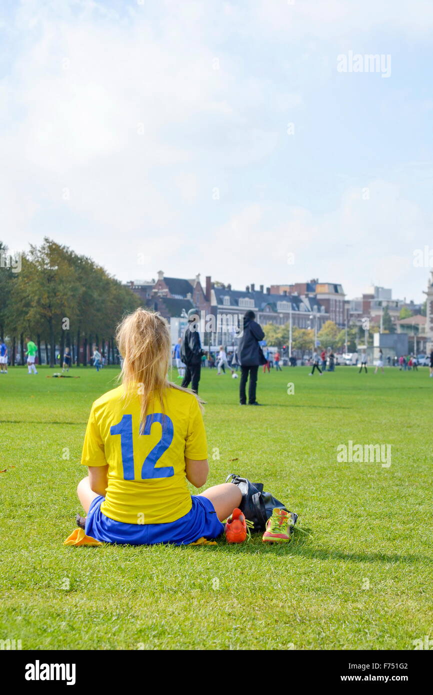 Ragazza su una pausa da un gioco del calcio seduto in un parco Foto Stock