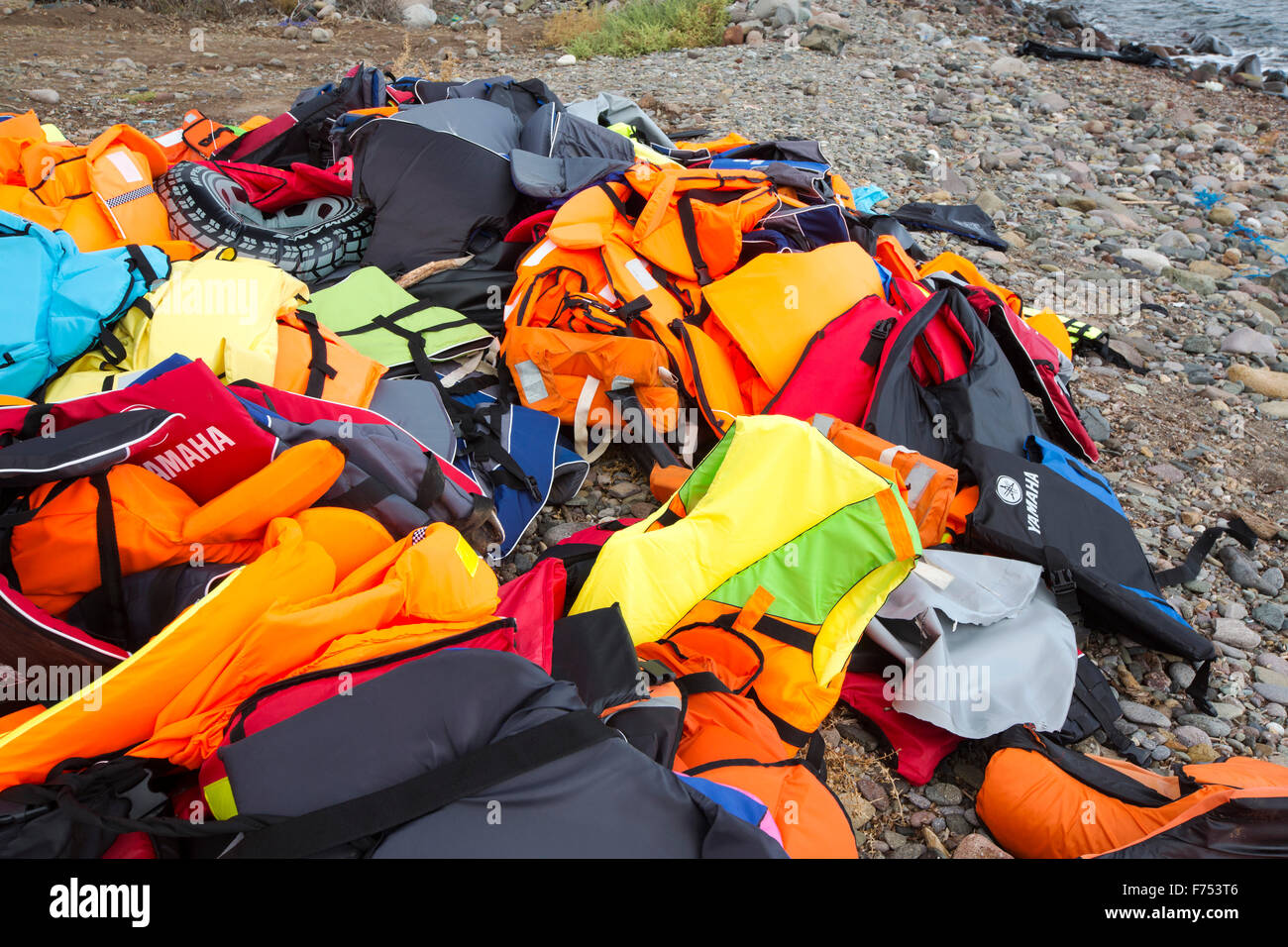 Giubbotti di salvataggio e resti di imbarcazioni a sinistra da immigrati siriani che fuggono dalla guerra e la fuga verso l'Europa, lo sbarco nell'isola greca di Lesbo sulla costa nord a Efthalou. Fino a 4 mila migranti un giorno sbarcano sull isola e schiacciante le autorità. Essi sono traficked illegale dal popolo turco i trafficanti che carica fino a 2.000 dollari a persona per mezza ora di viaggio in un sovraffollamento inflateable barca dalla terraferma turco a Lesbo. Foto Stock