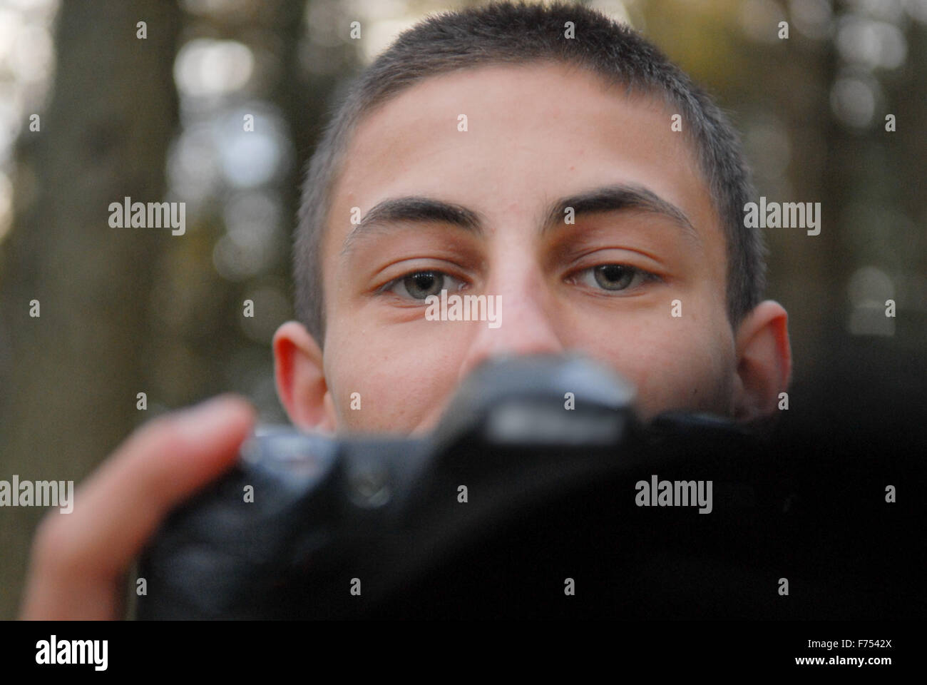 Ragazzo adolescente con fotocamera reflex digitale nella foresta. Foto Stock