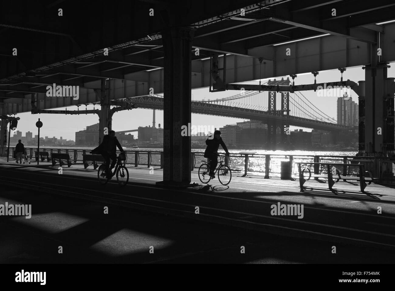 Due uomini ciclo e un altro passeggiate lungo la East River Esplanade, New York Foto Stock