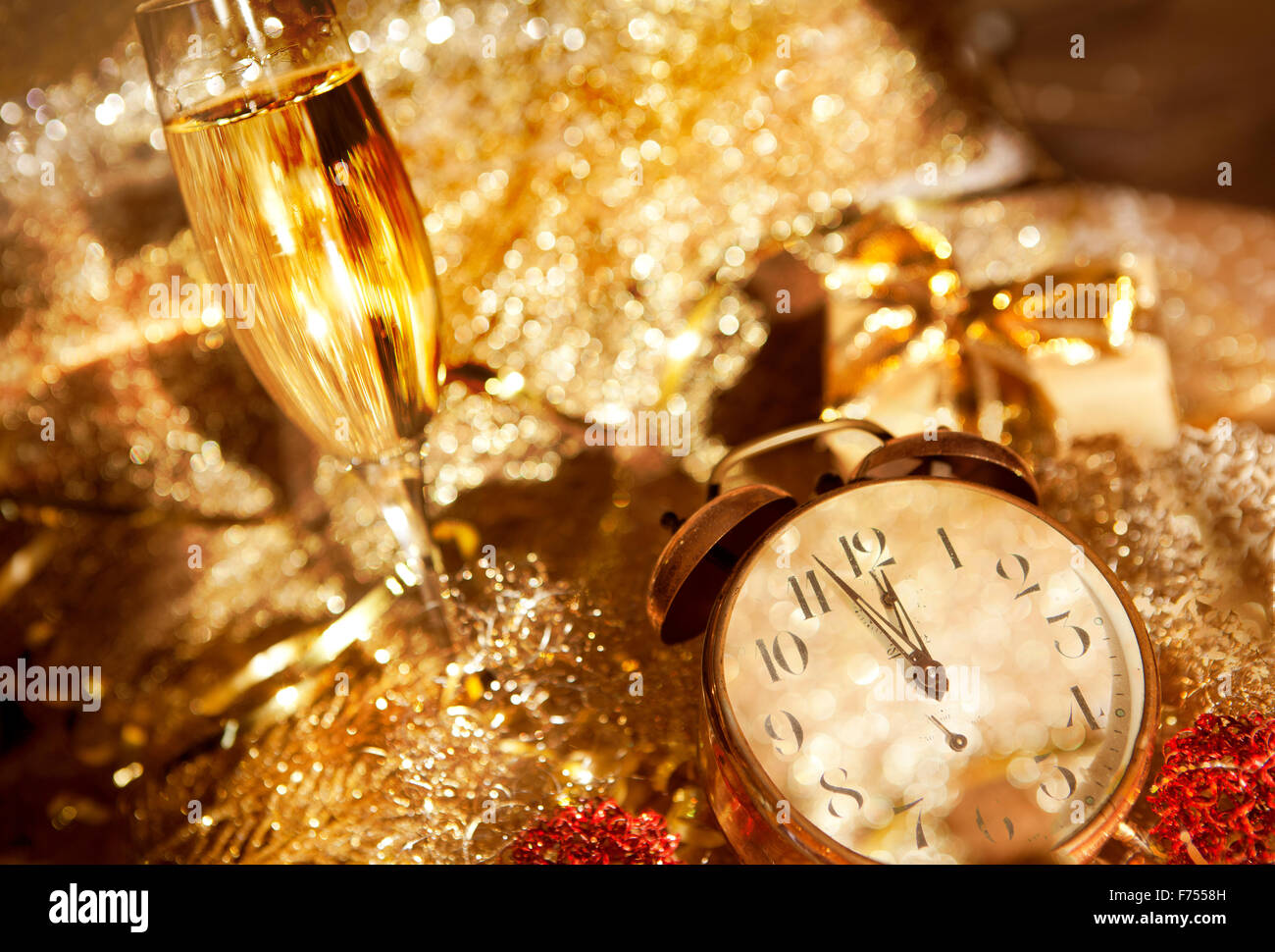 Un orologio viene visualizzato appena prima del nuovo anno, in background champagne e decorazione festa di Capodanno Foto Stock