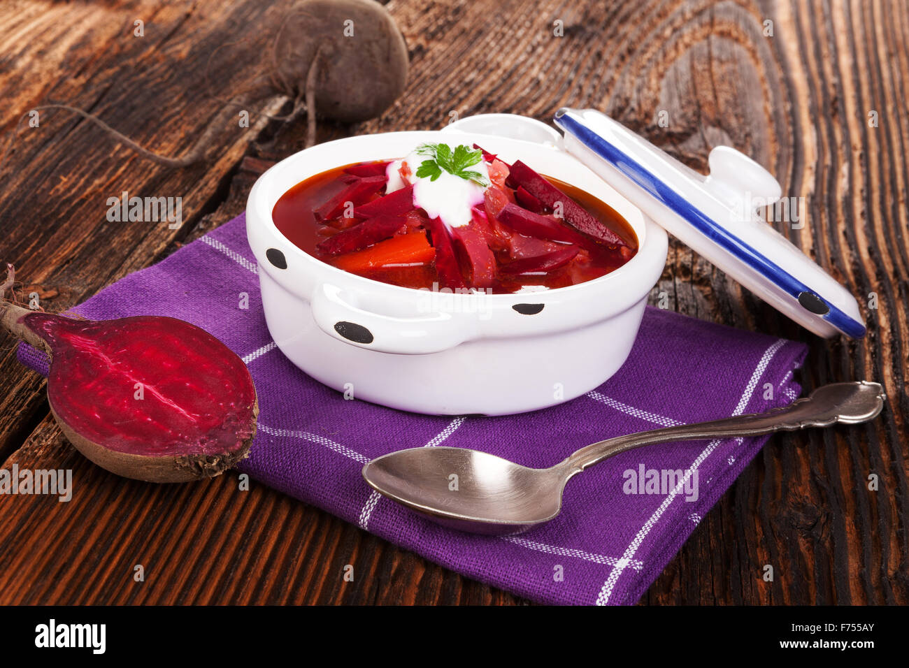 Deliziosi borsch ucraino zuppa con barbabietola fresca su vegetali porpora su tavola in legno rustico. Cucina tradizionale Foto Stock