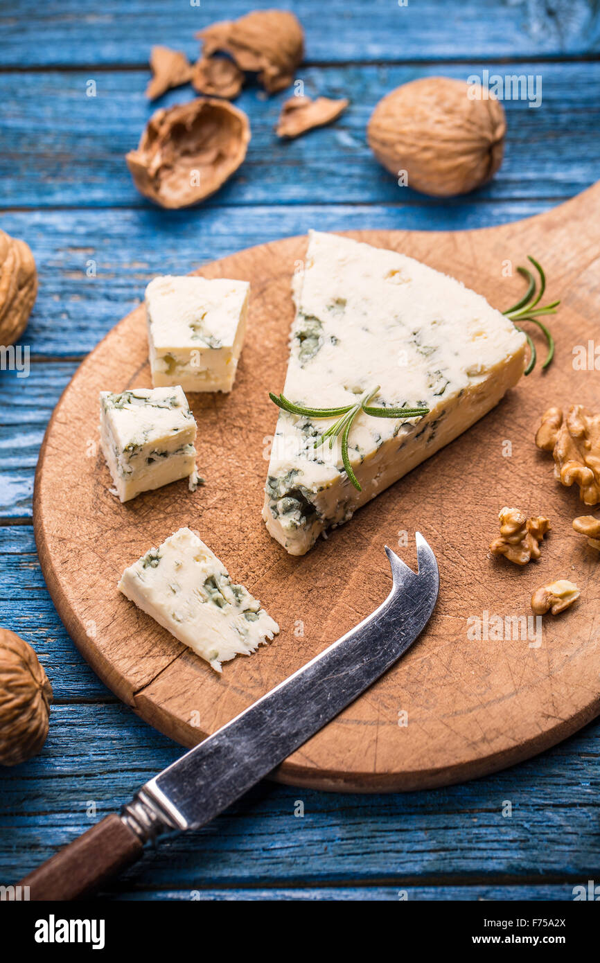Gustoso formaggio blu con il dado sul tagliere di legno Foto Stock