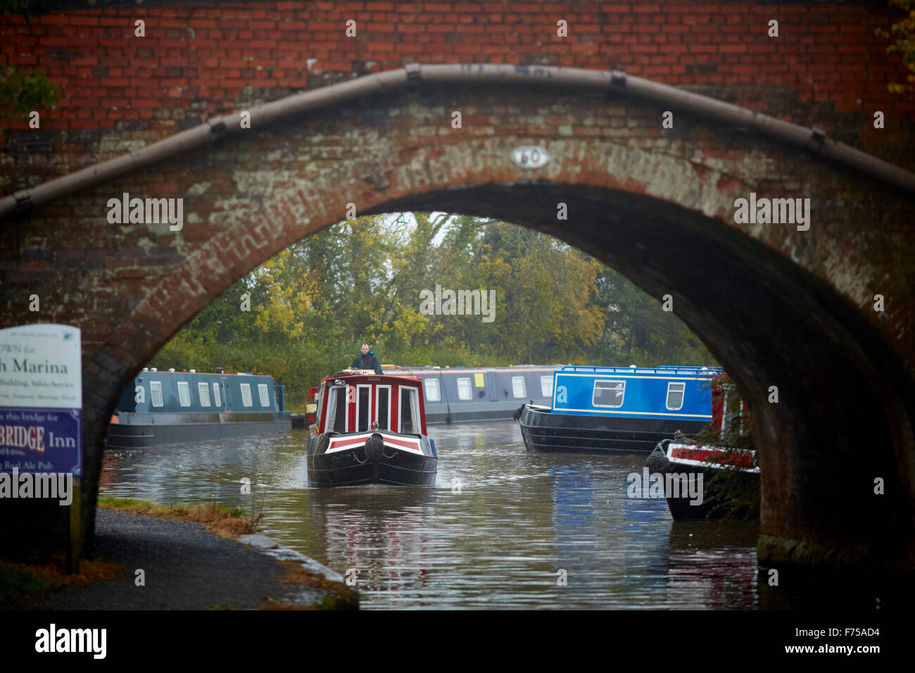 Alvechurch in Worcestershire marina fluviale boat yard blu nebbia canal autunno in movimento attraverso il ponte di arco sotto UK Gran Br Foto Stock