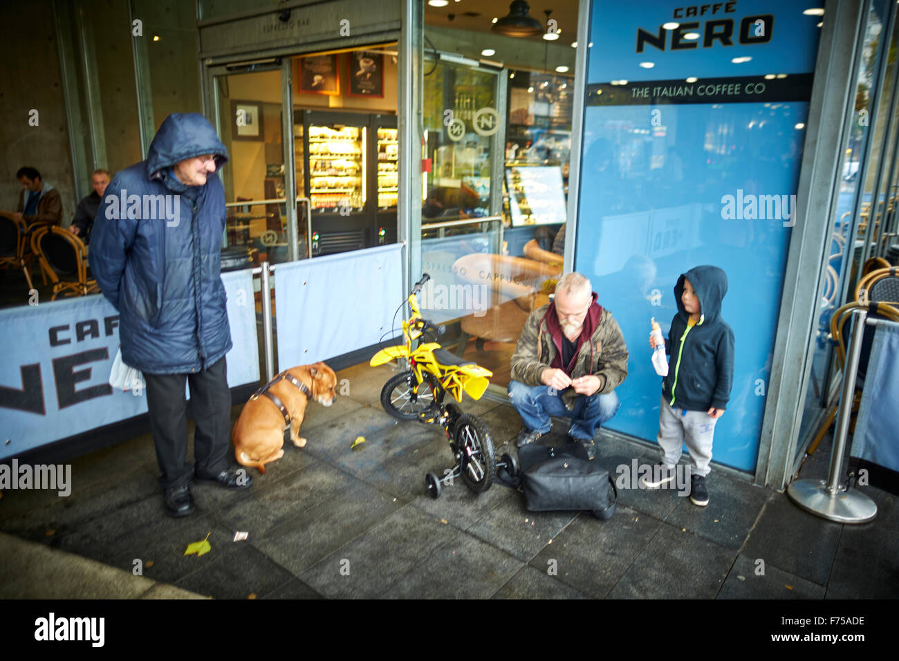 Cafe Nero caffe al di fuori del giovane ragazzo in bici in attesa di mangiare il cane di essere guardato felice Piccadilly Gardens Manchester uomo uomini il suo maschio hi Foto Stock