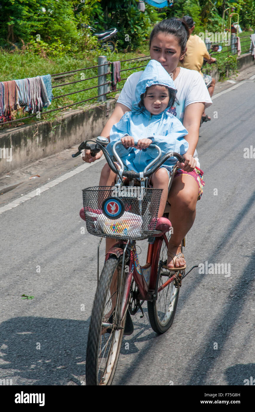 Bambino Bicicletta Equitazione con sua madre in un quartiere residenziale di dhonburi, bangkok, Thailandia Foto Stock