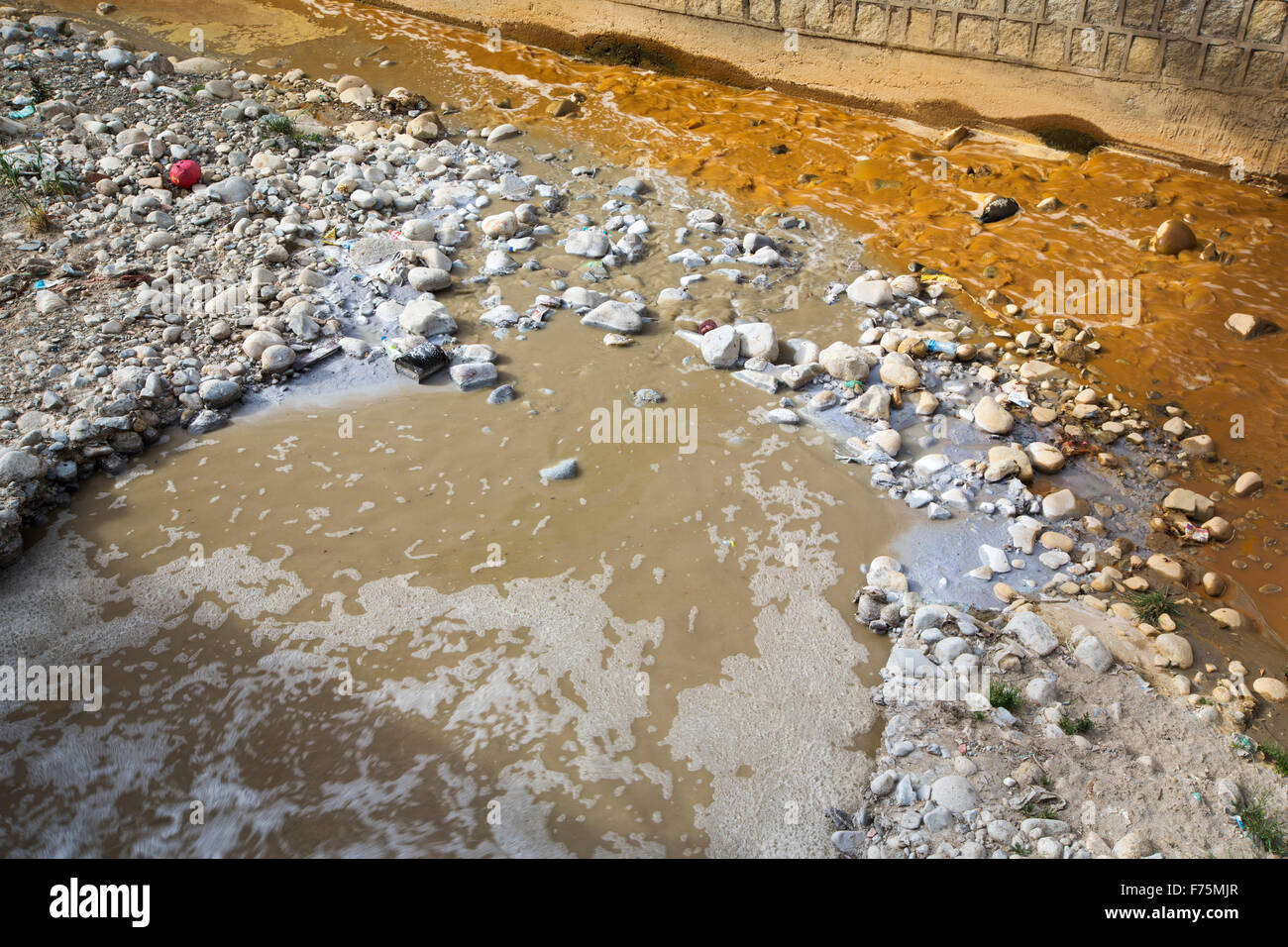 Un fiume pieno di acqua contaminata da miniera effluente, miscelazione con liquame crudo a La Paz, in Bolivia. La Paz sarà probabilmente la prima città capitale del mondo che dovrà essere in gran parte abbandonato a causa di mancanza di acqua. Essa si basa principalmente su acqua di disgelo glaciale dal circostante picchi andini, ma come il cambiamento climatico provoca i ghiacciai a fusione, si è rapidamente a corto di acqua. Foto Stock