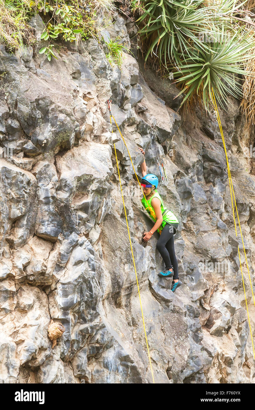 Banos, Ecuador - 30 Novembre 2014: la sfida di basalto del Tungurahua, giovane ragazza latina da Ecuador salendo una verticale Parete di roccia Foto Stock