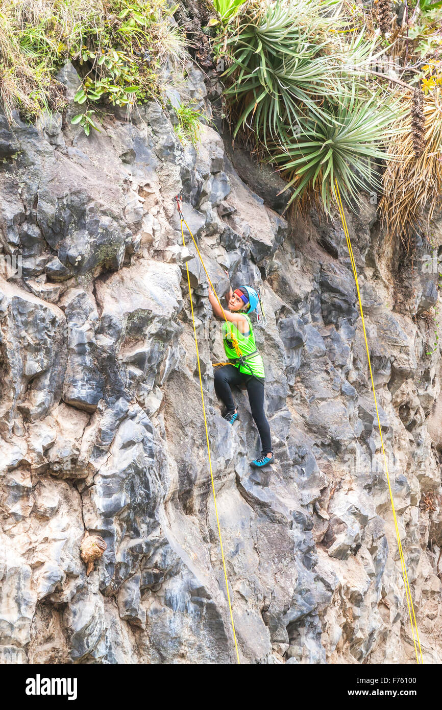 Banos, Ecuador - 30 Novembre 2014: la sfida di basalto del Tungurahua, Teen ragazza latina salendo una verticale Parete di roccia, Sud America Foto Stock
