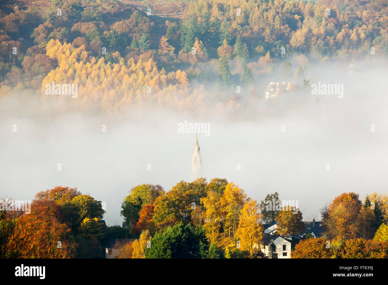 Guardando verso il basso sulla Ambleside con nebbia a valle nel periodo autunnale, Lake District, UK, con la chiesa di Santa Maria la guglia inserimenti attraverso la nebbia. Foto Stock