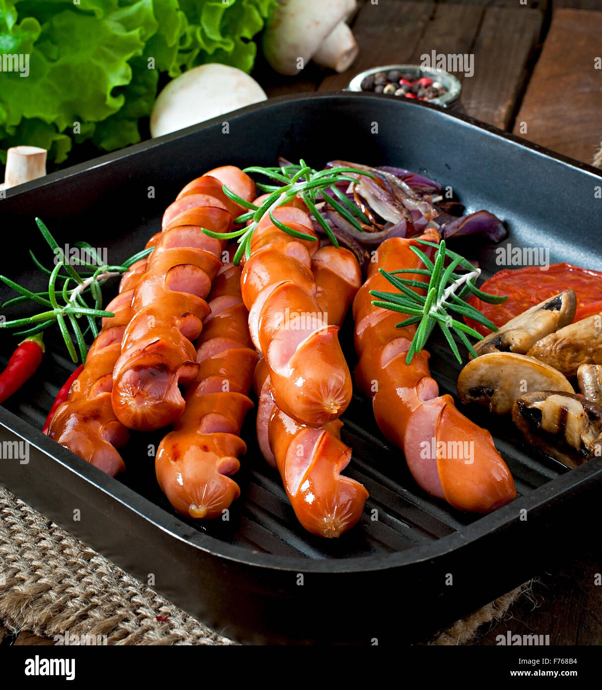 Salsicce alla griglia con le verdure su una padella Foto Stock