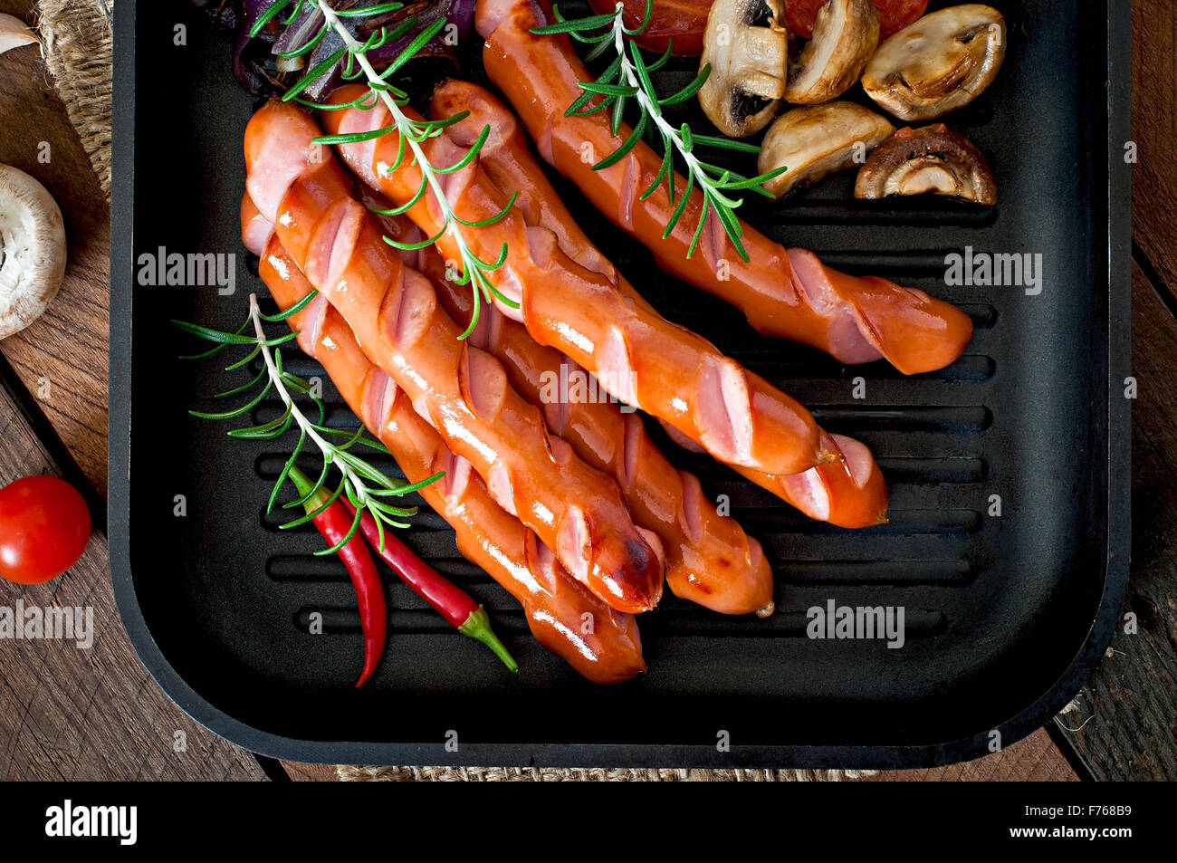 Salsicce alla griglia con le verdure su una padella. Vista superiore Foto Stock