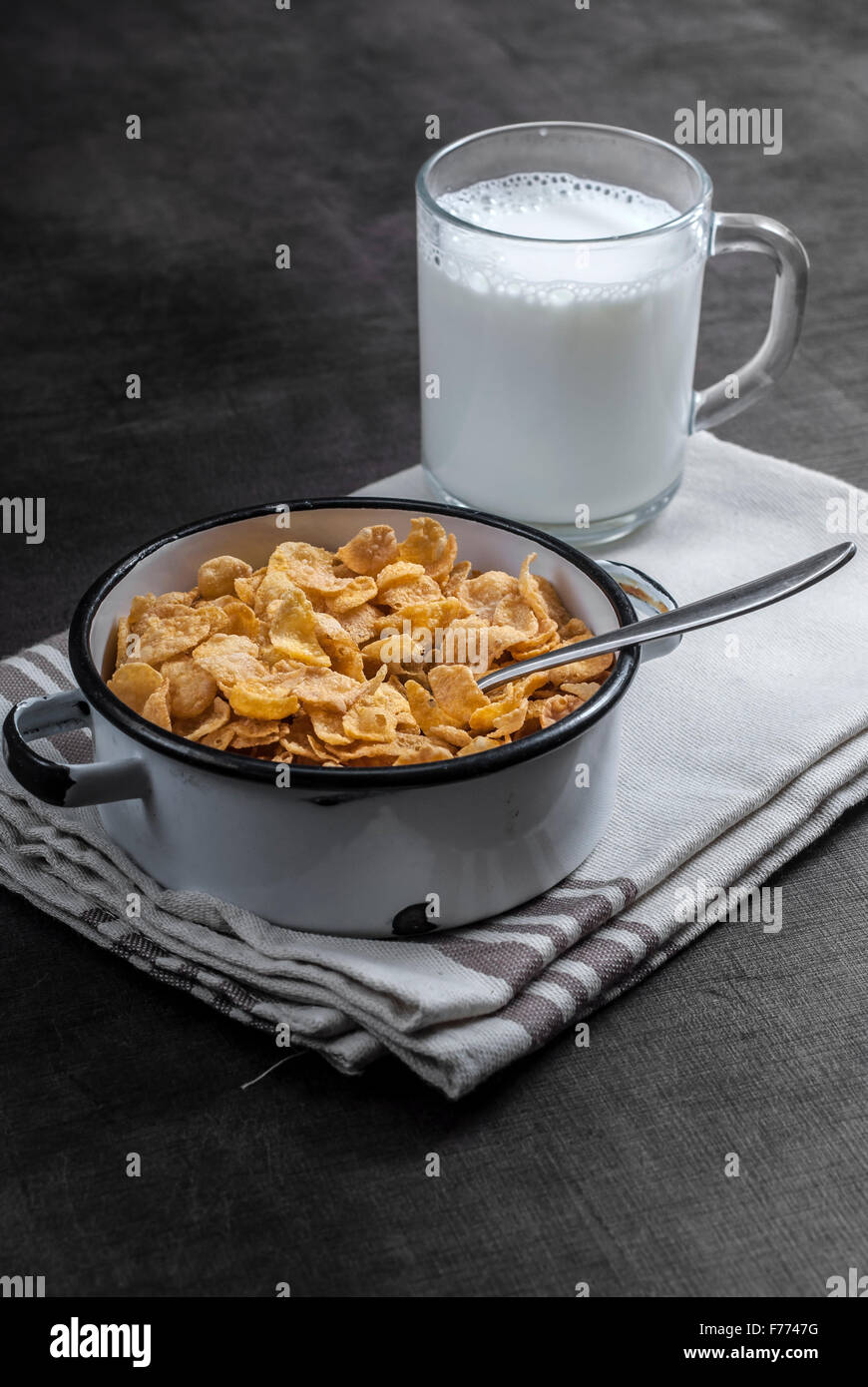 Fiocchi di mais e bicchiere di latte sulla superficie di legno Foto Stock