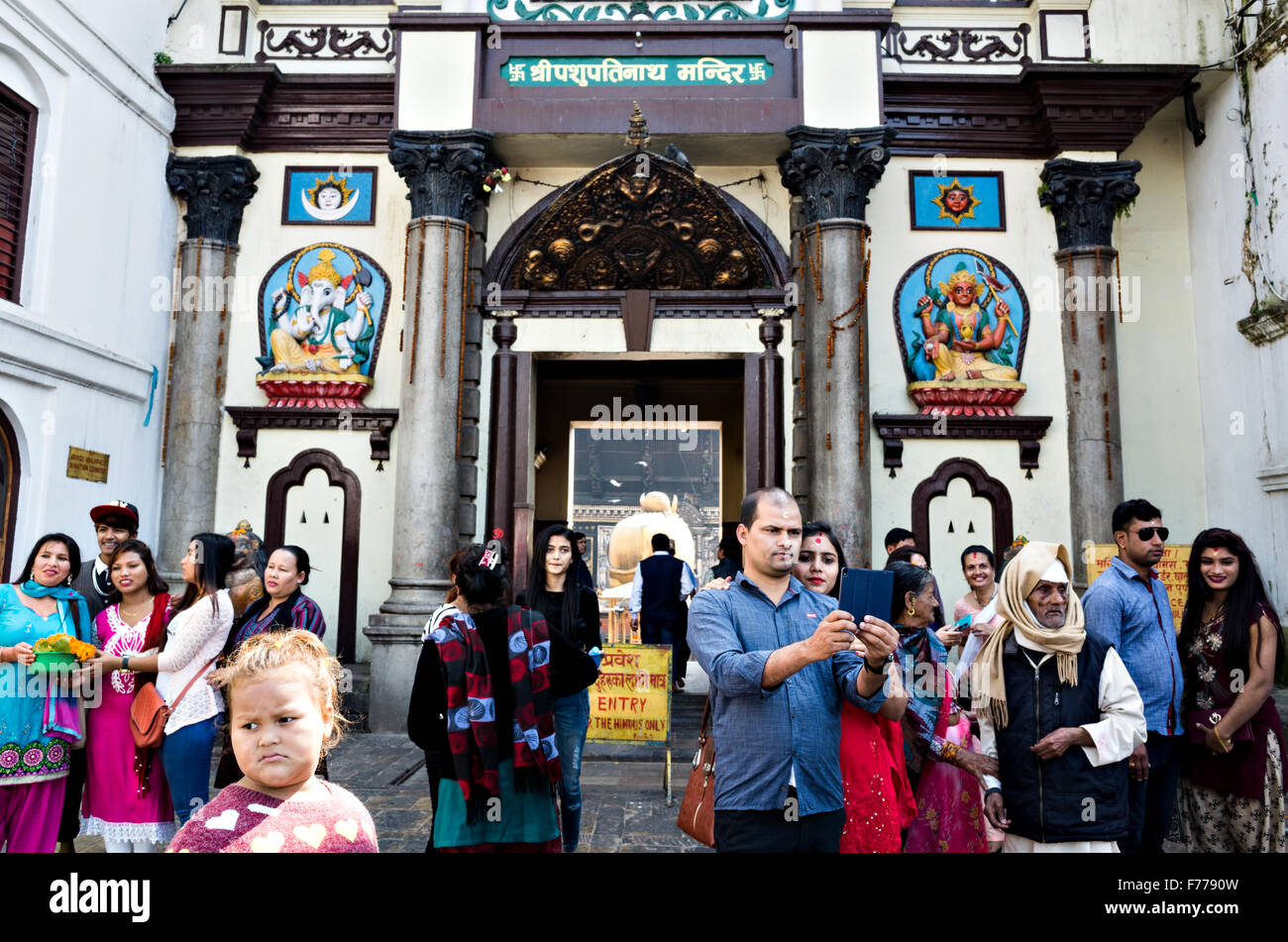 I diversi gruppi di persone e di turisti scattano fotografie di fronte all'entrata nel tempio di Pashupatinath, Kathmandu Foto Stock