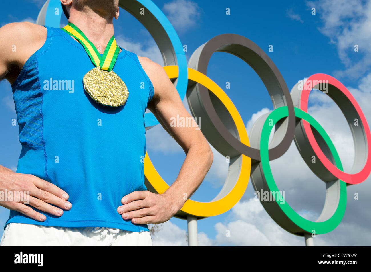 LONDON, Regno Unito - 14 ottobre 2015: Medaglia d'oro atleta sta in piedi di fronte ad anelli olimpici nel Queen Elizabeth Olympic Park. Foto Stock
