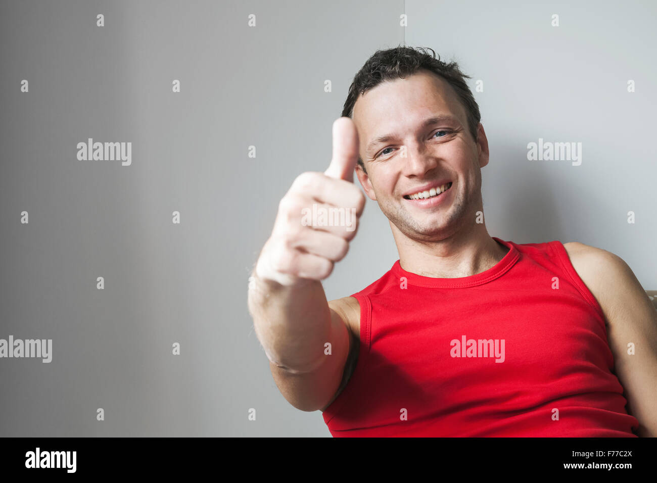 Positivo sorridente giovane uomo caucasico mostra Thumbs up gesto, ritratto in studio Foto Stock
