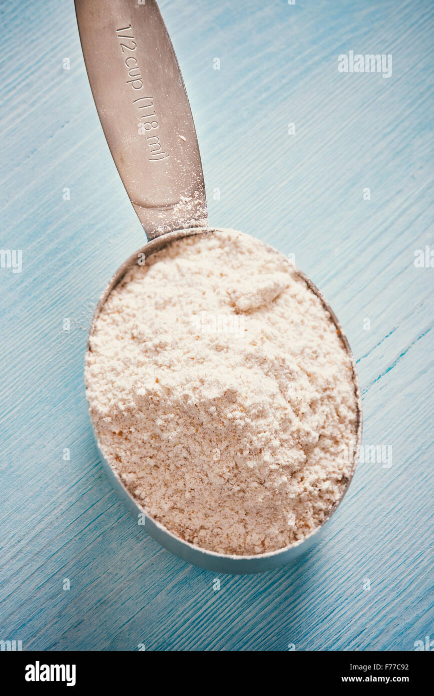La coppa di misurazione cucchiaio con farina blu sul tavolo di legno Foto Stock