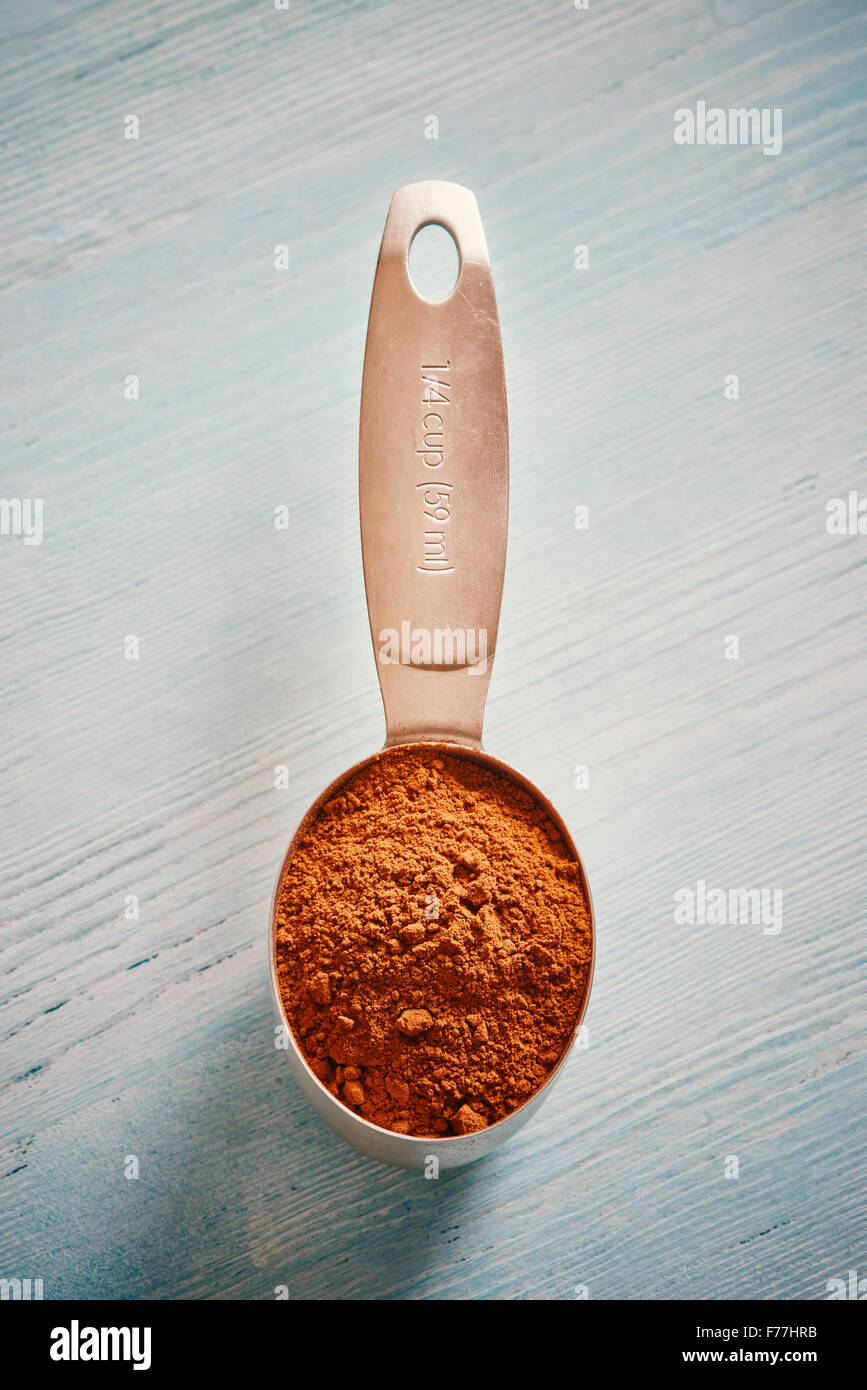 La coppa di misurazione cucchiaio con cacao blu sul tavolo di legno Foto Stock