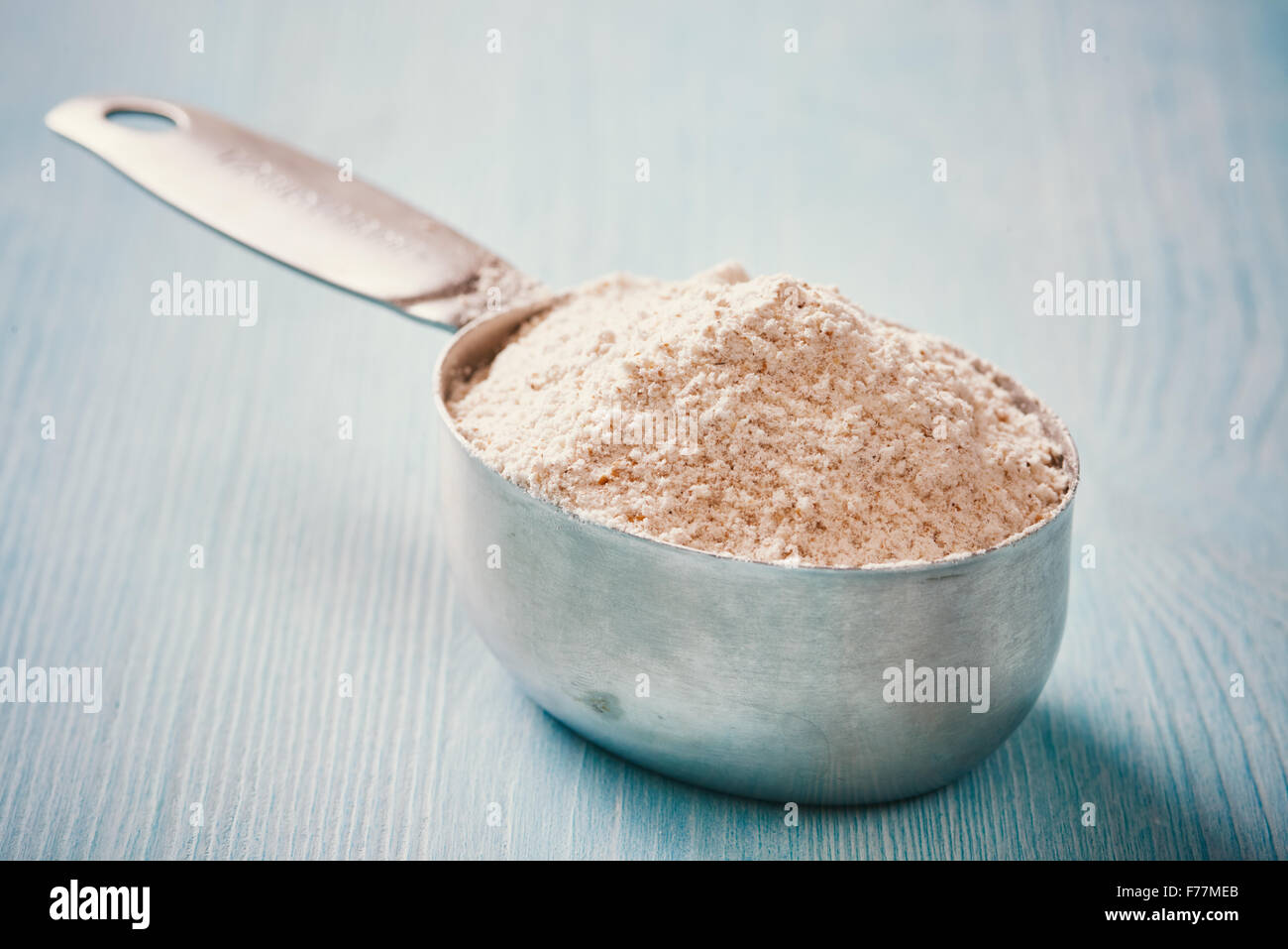 La coppa di misurazione cucchiaio con farina blu sul tavolo di legno Foto Stock