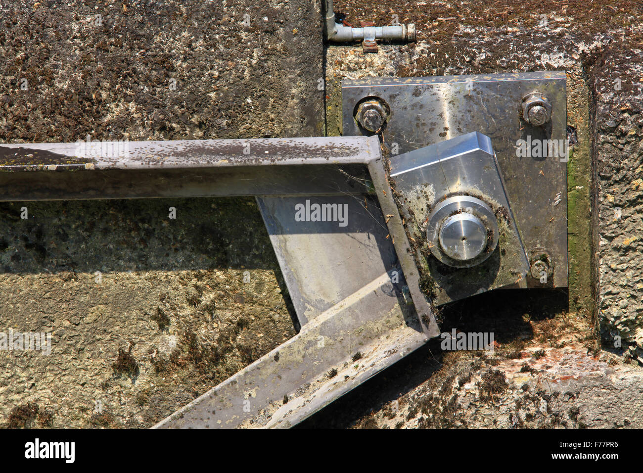 Un acciaio inossidabile braccio basculante su un perno di cerniera fissato ad un muro di cemento in un ambiente acquatico. Foto Stock