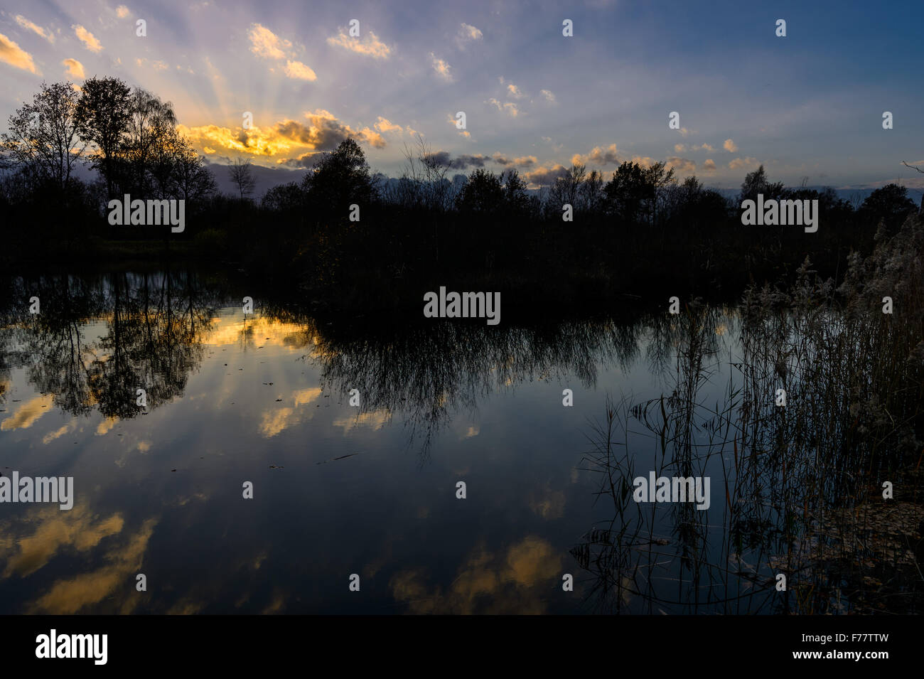 Tramonto con nubi rosse e riflettendo in acqua di un lago di torba. Korenburgerveen, Winterswijk, Paesi Bassi Foto Stock