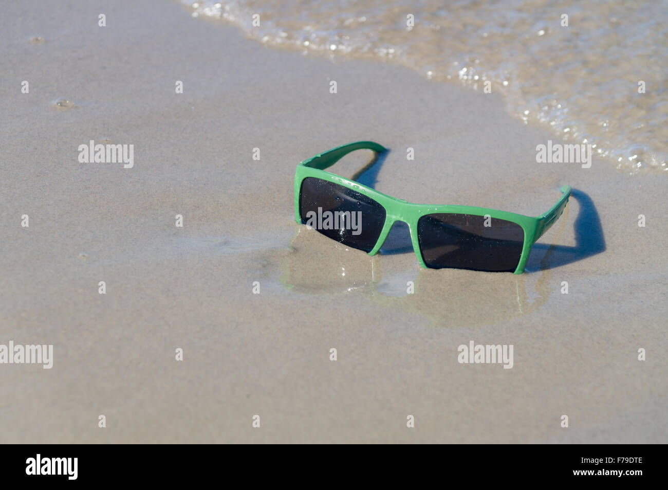 Occhiali da sole verde sulla spiaggia e wave è venuta Foto Stock