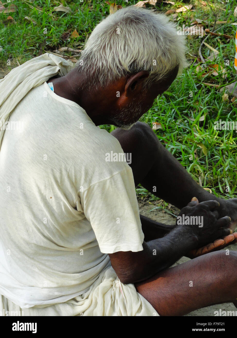 Ritratto: il povero vecchio uomo dall India siede sulla terra Foto Stock